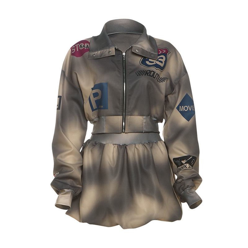 Two-piece bomber jacket and skirt set with vintage-inspired patches, featuring a cropped jacket and high-waisted mini skirt in muted tones.

